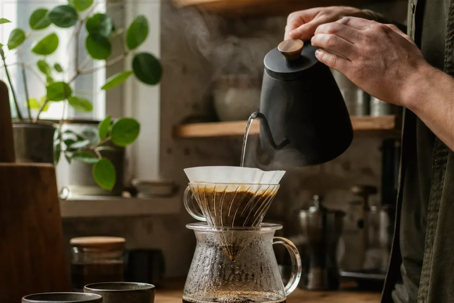 Filterkaffee wird mit einem Schwanenhalskessel von Hand in einer Küche aufgegossen – gezeigt für Jura im Markenprofil.