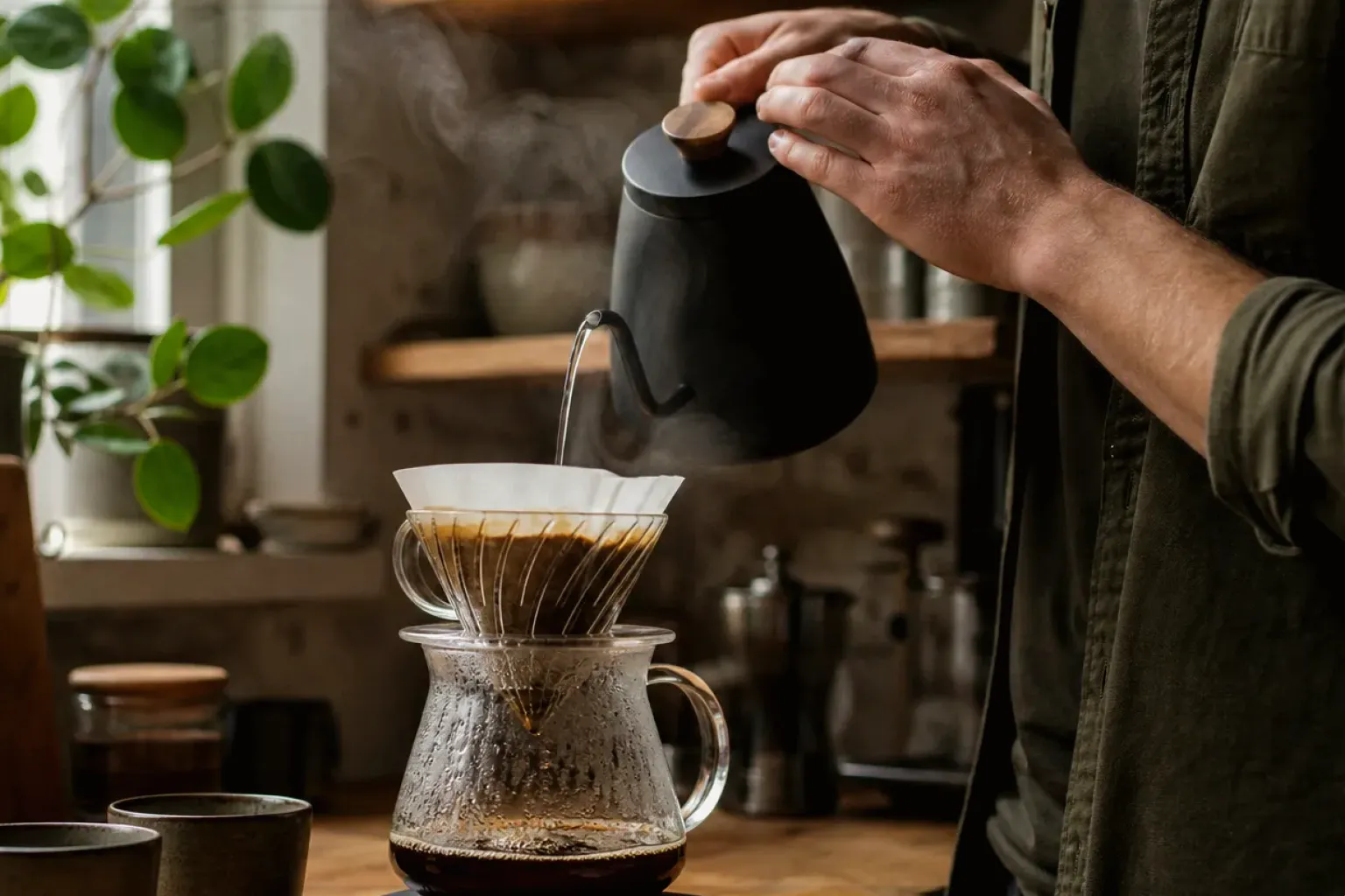 Filterkaffee wird mit einem Schwanenhalskessel von Hand in einer Küche aufgegossen – gezeigt für Melitta im Markenprofil.