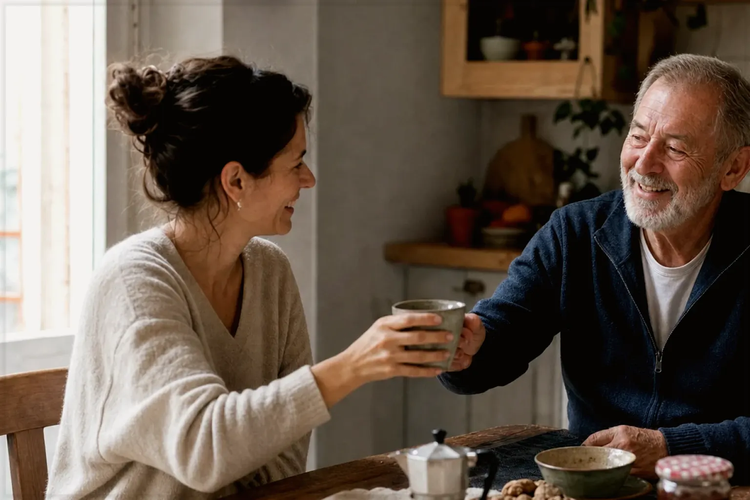 Eine erwachsene Tochter und ihr älterer Vater lachen gemeinsam beim Kaffee in ihrer Küche – gezeigt für Säurearm im Themenvergleich.